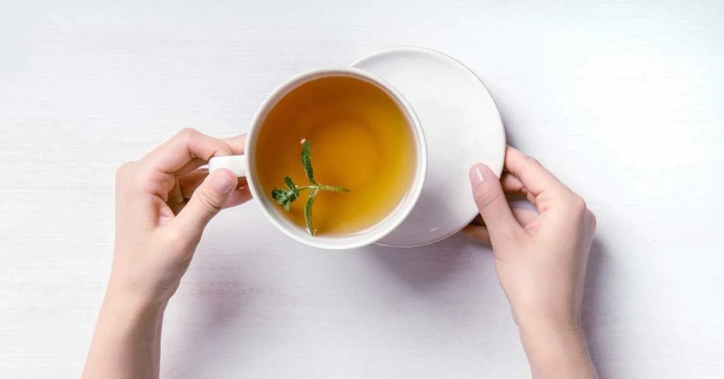 دمنوش فنجان سفید در دست